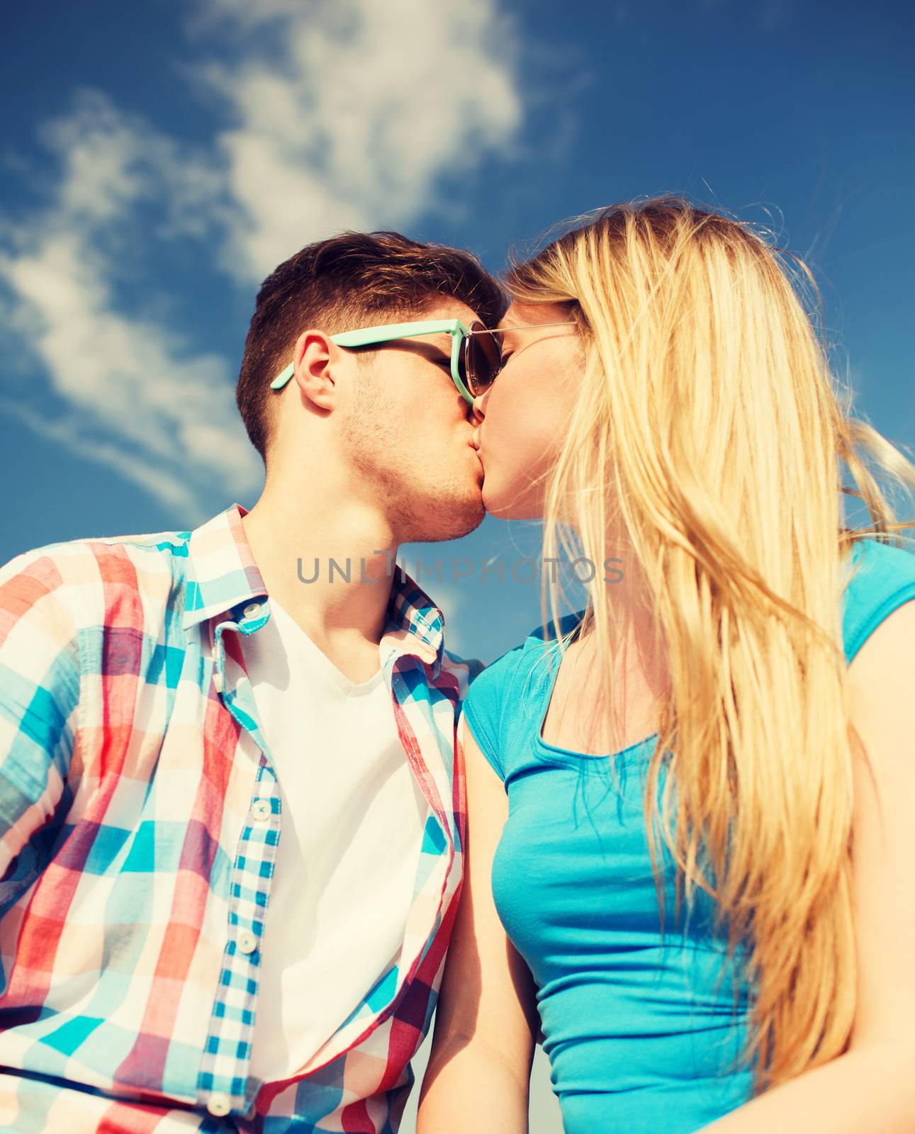 holidays, vacation, love and friendship concept - smiling couple kissing outdoors