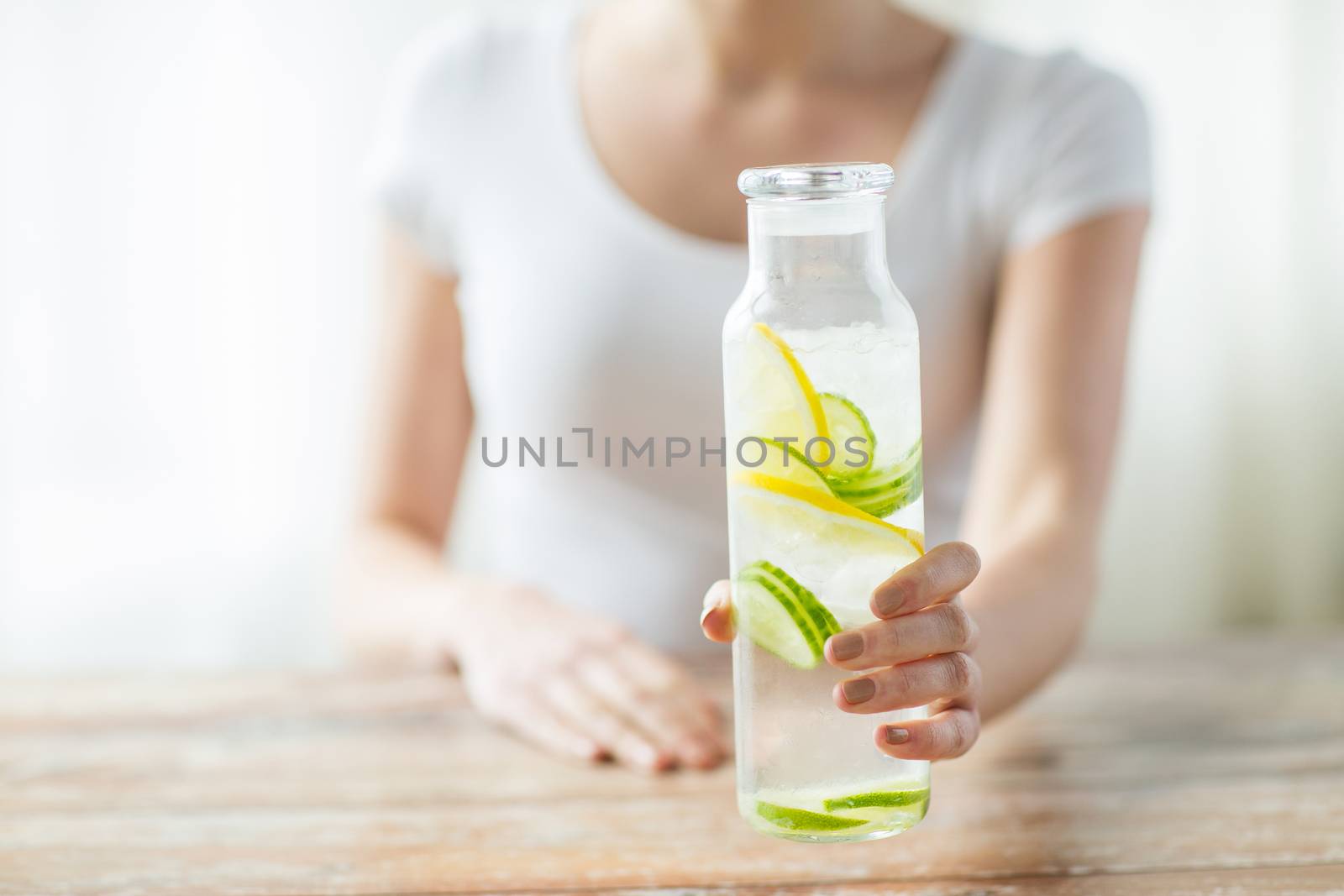 close up of woman with fruit water in glass bottle by dolgachov