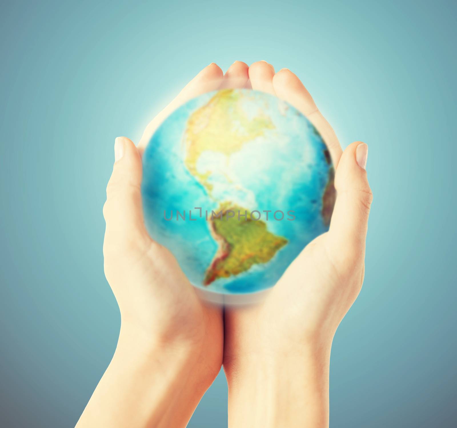 people, geography, population and peace concept - close up of human hands with earth globe showing american continent over blue background