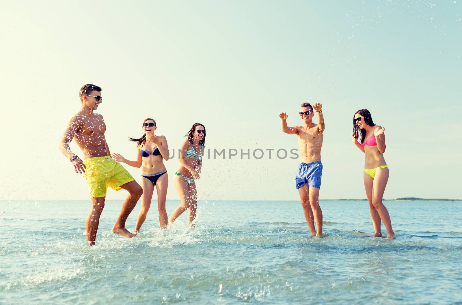 friendship, sea, summer vacation, holidays and people concept - group of happy friends having fun on summer beach