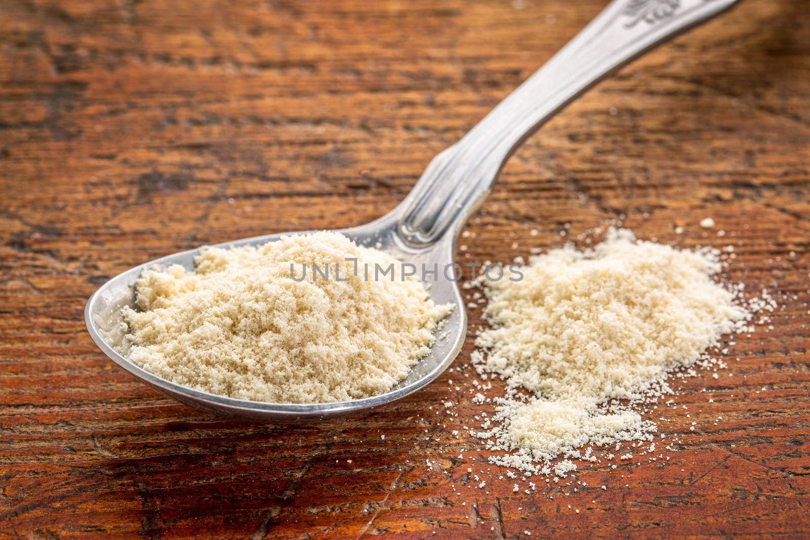 tablespoon of whey protein powder against rustic scratched wood background
