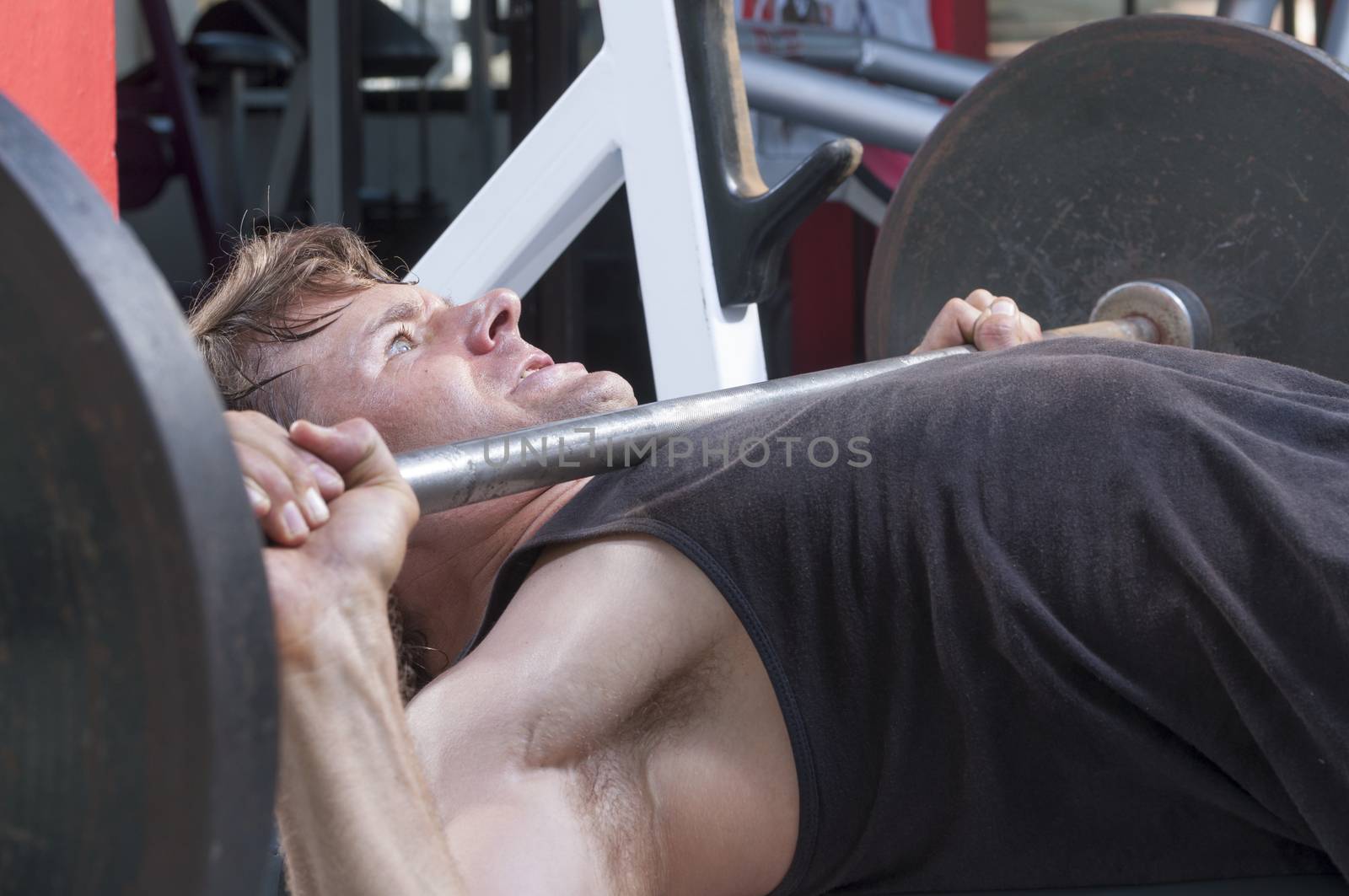 Closeup of Caucasian man performing high bench press with heavy barbell