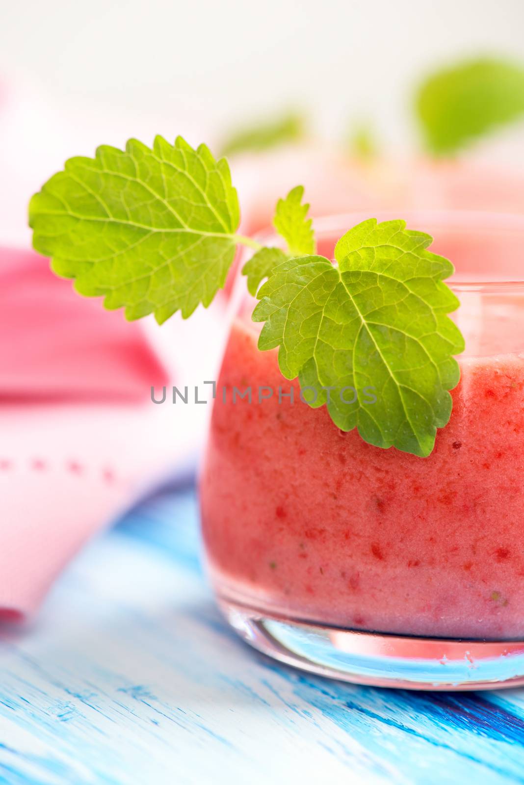 Smoothie drink with mint leafs on table, in high key