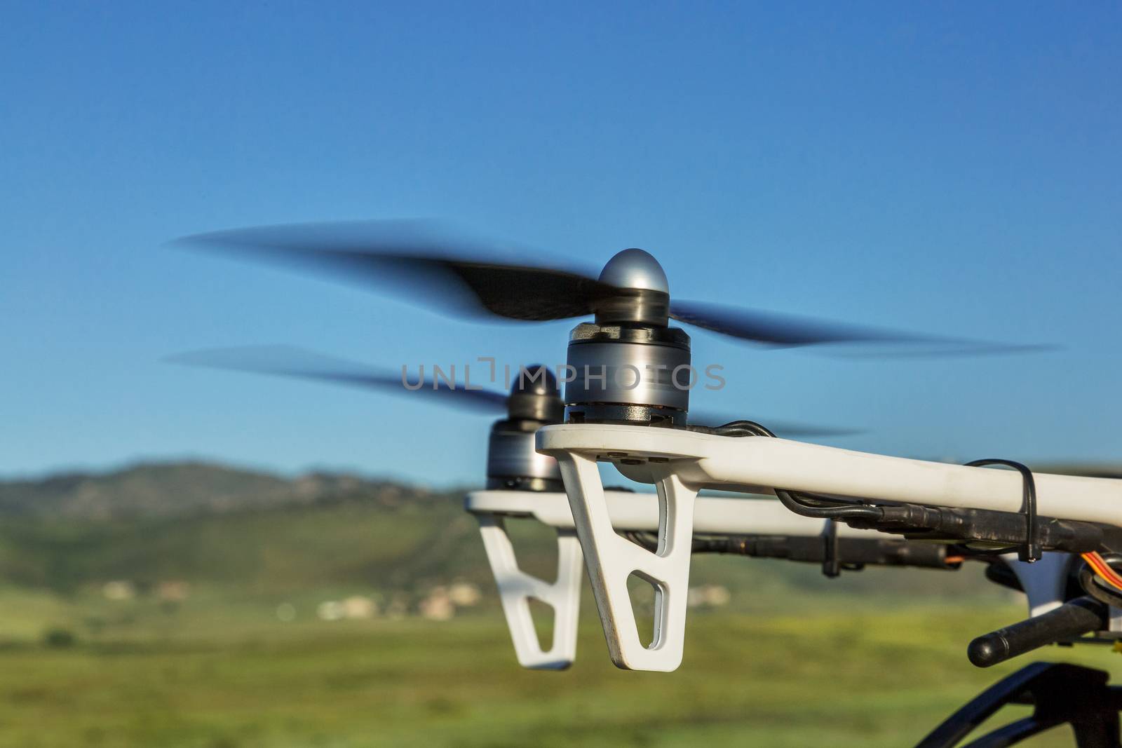 blurred spinning propellers of a hexacopter drone flying over foothills prairie
