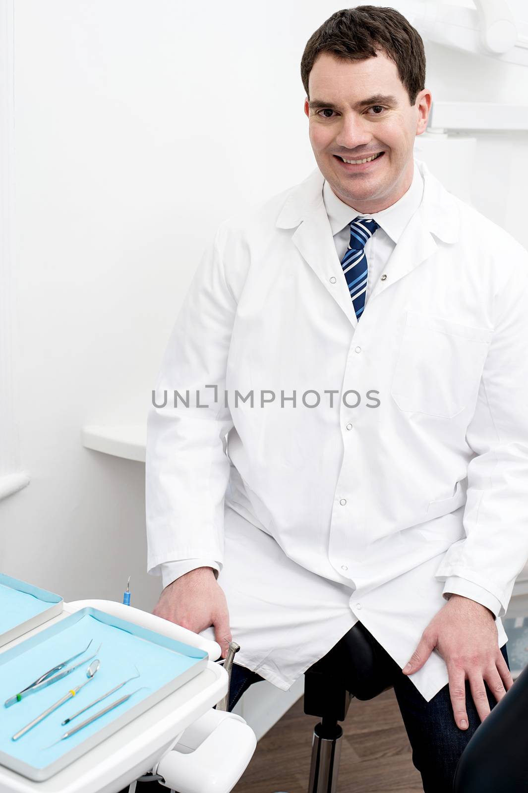 Happy male dentist smiling at dental clinic