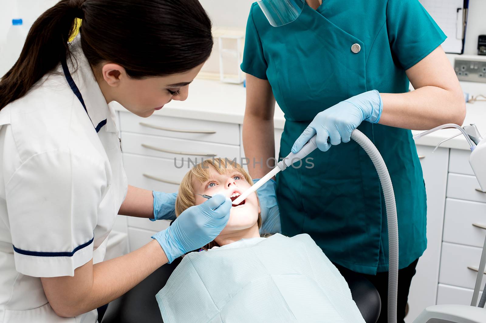 Dentist and assistant curing little girl