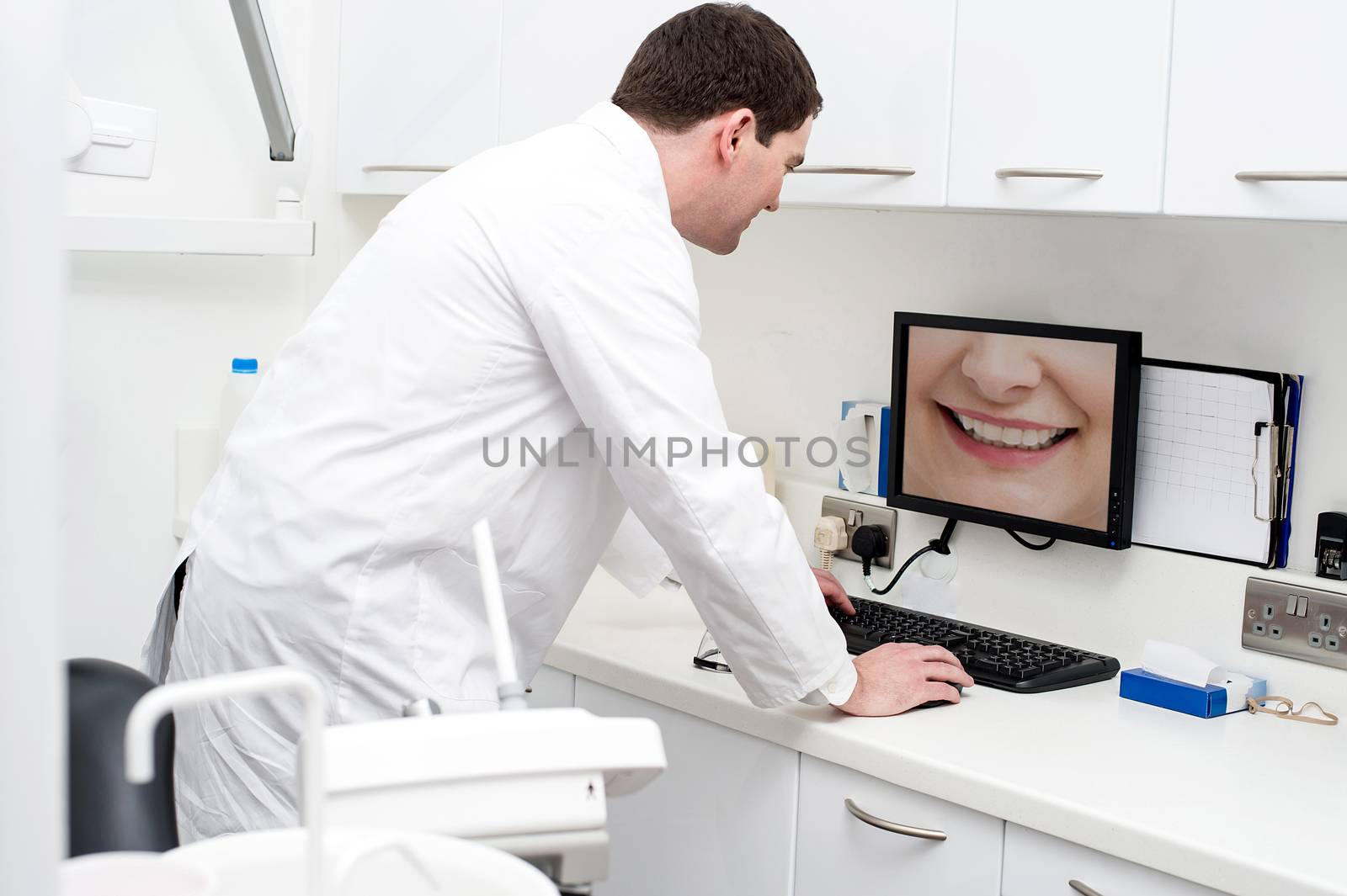 Dentist using computer in dental clinic by stockyimages