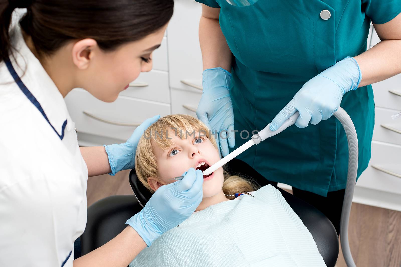 Dental assistant treat a little girl by stockyimages