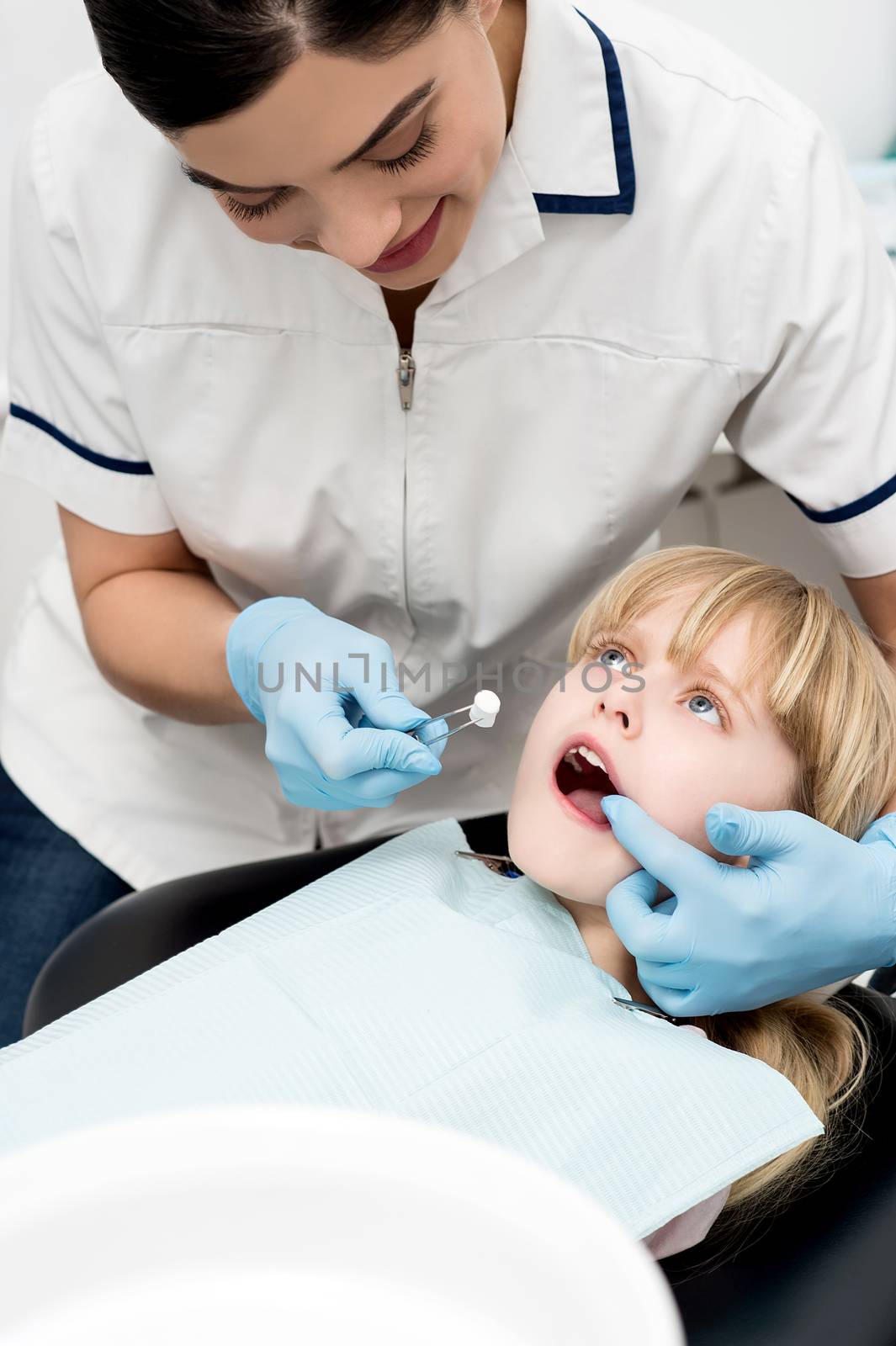 Cute kid examined by dental assitant by stockyimages