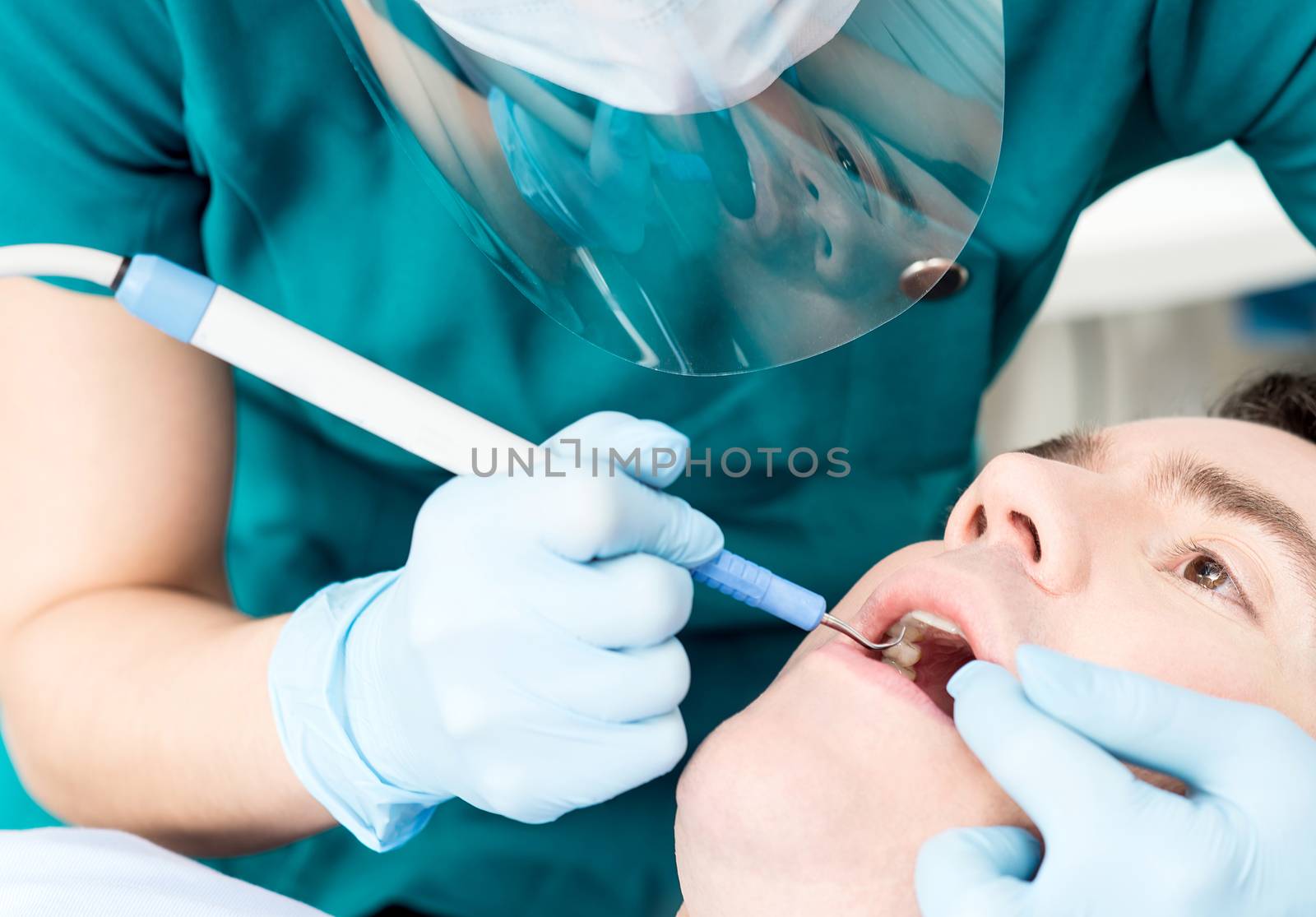 Close up of dentist treat a man teeth by stockyimages