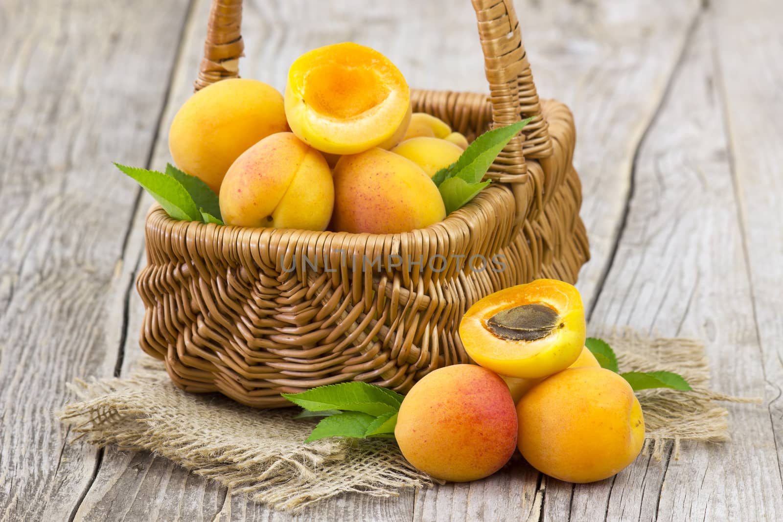fresh apricots in a basket on wooden background by miradrozdowski