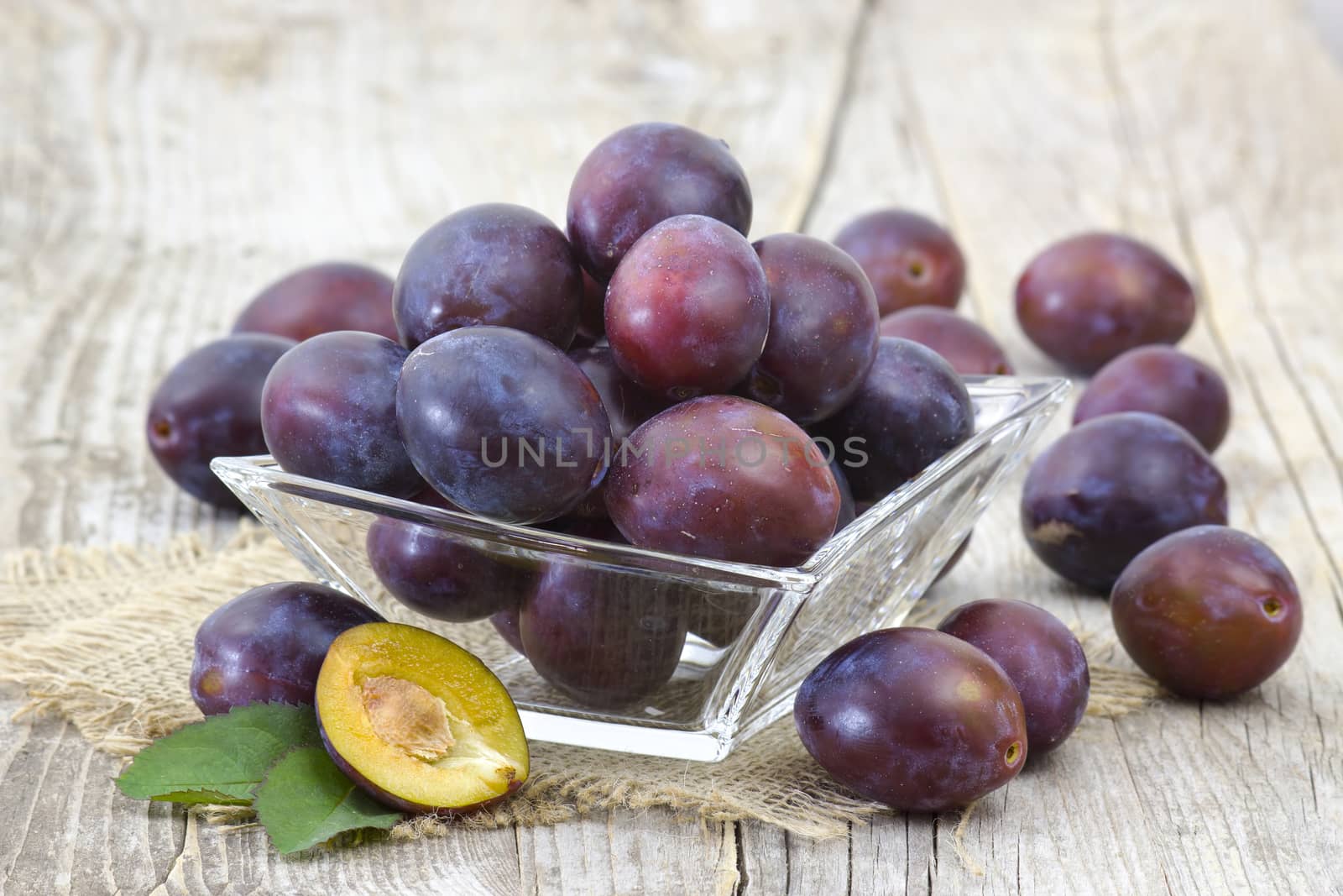 fresh plums in a bowl on old wooden background