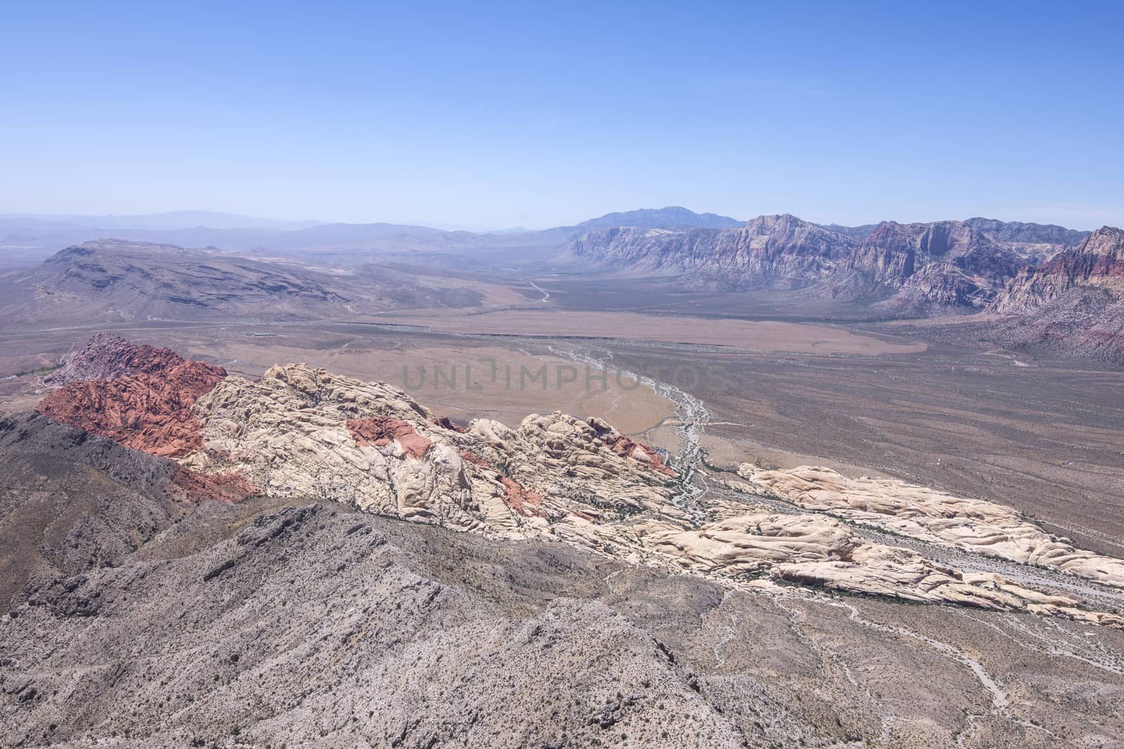 Wide scenic high angle view of Red Rock Canyon, Nevada under clear blue sky with colored rock formations seen from top of Turtle Head Peak