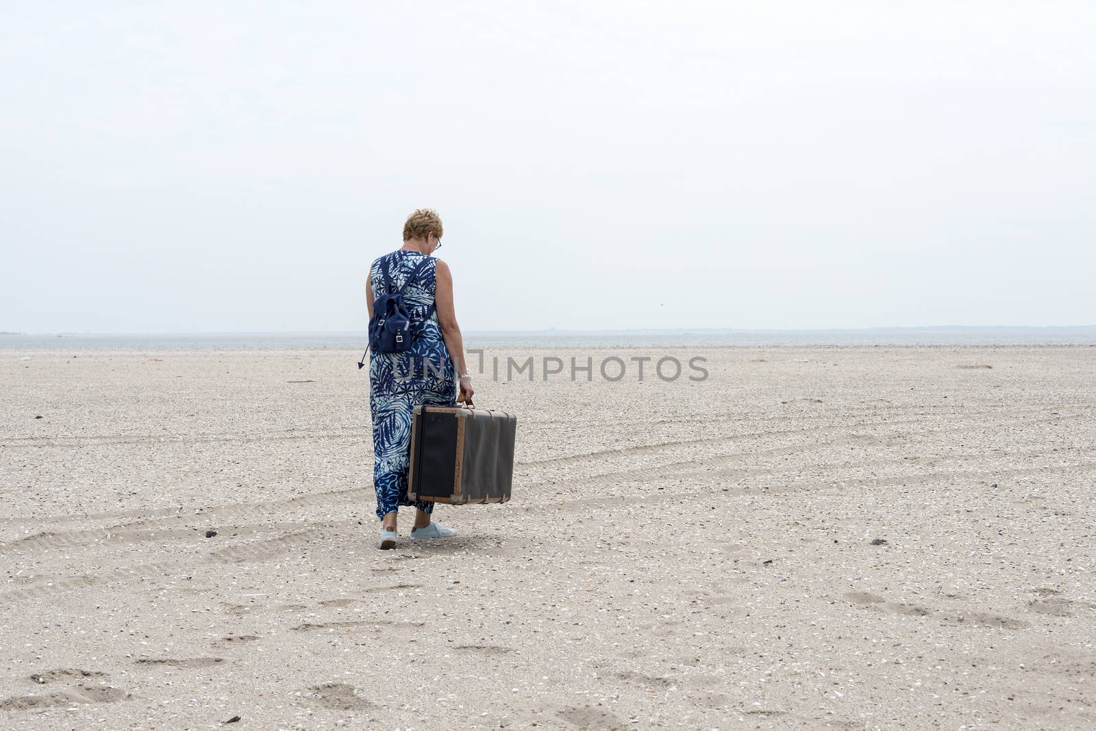 woman with old vintage used suitcase walking near the beach