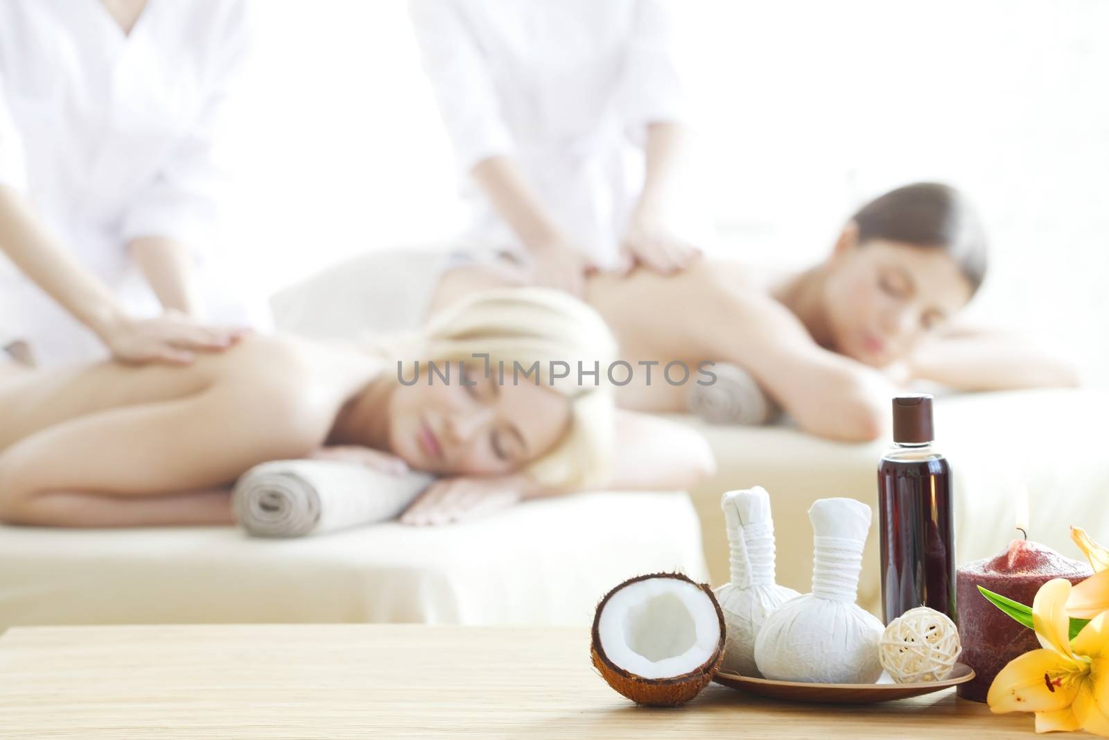 Spa massage tools and women getting massage on background