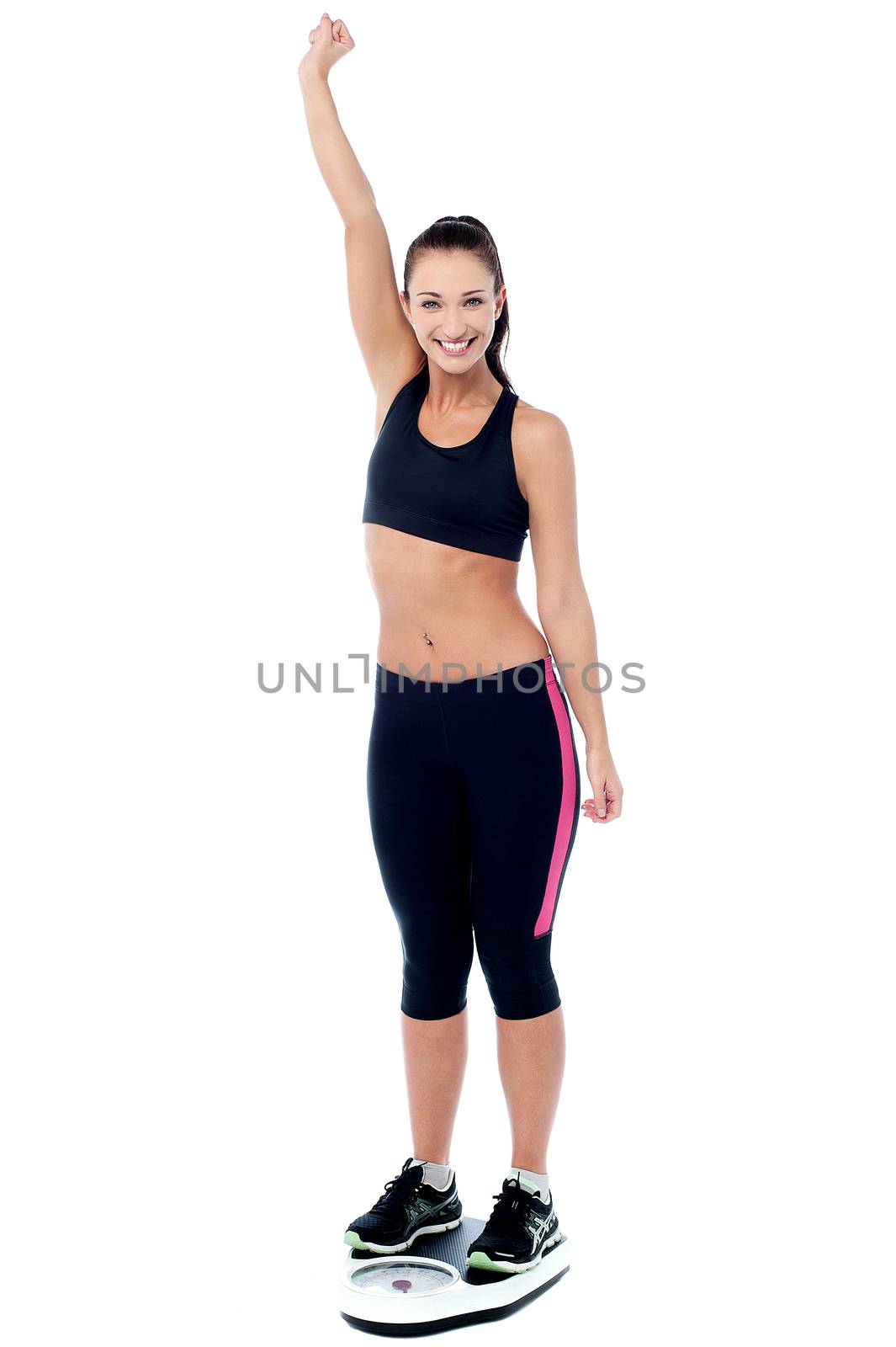 Excited young slim woman weighing herself.