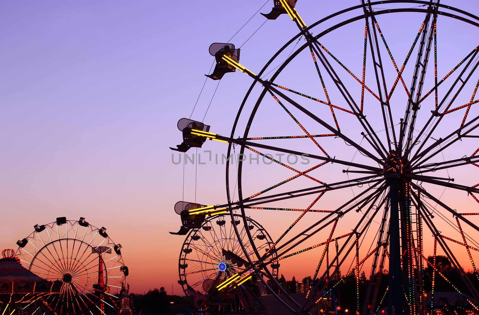 Silhouettes of carnival rides under sunset