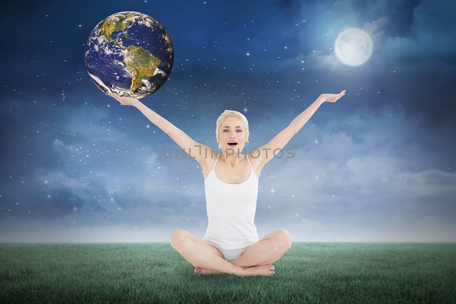 Toned young woman sitting with arms outstretched against green field at night