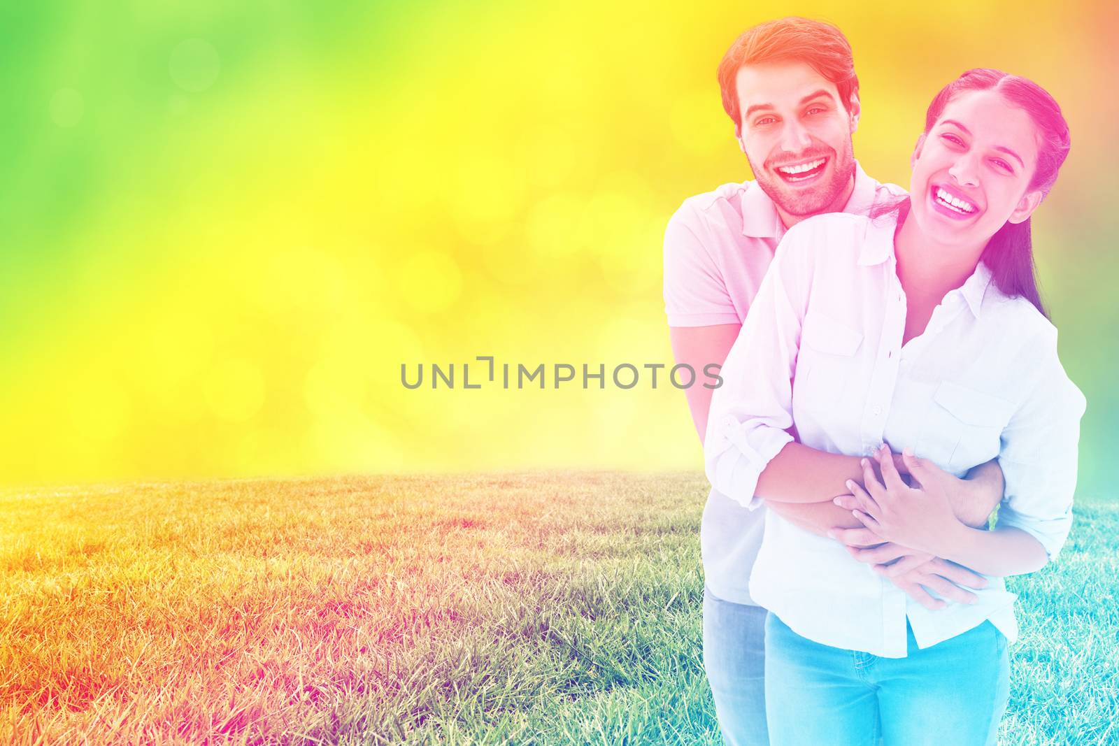 Cute couple hugging and smiling at camera against field against glowing lights
