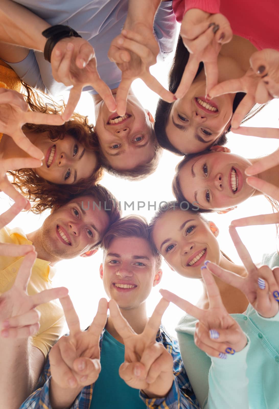 group of smiling teenagers showing victory sign by dolgachov