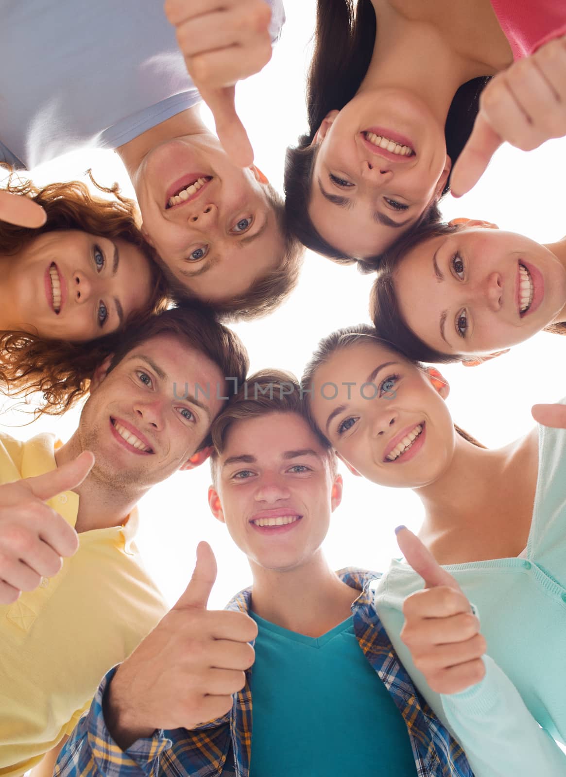 friendship, youth, gesture and people - group of smiling teenagers in a circle showing thumbs up