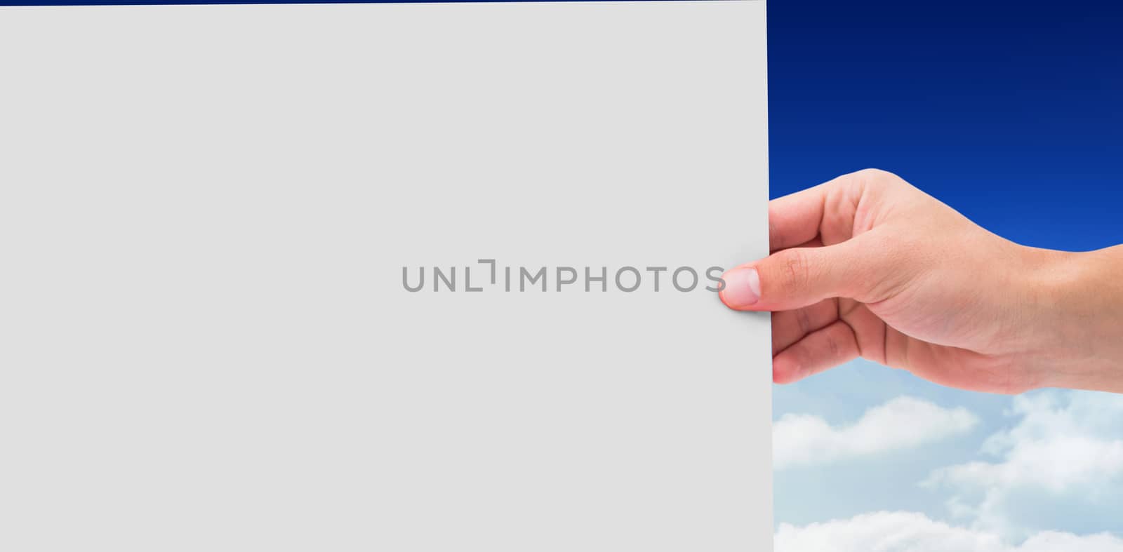 Hand showing card against bright blue sky over clouds