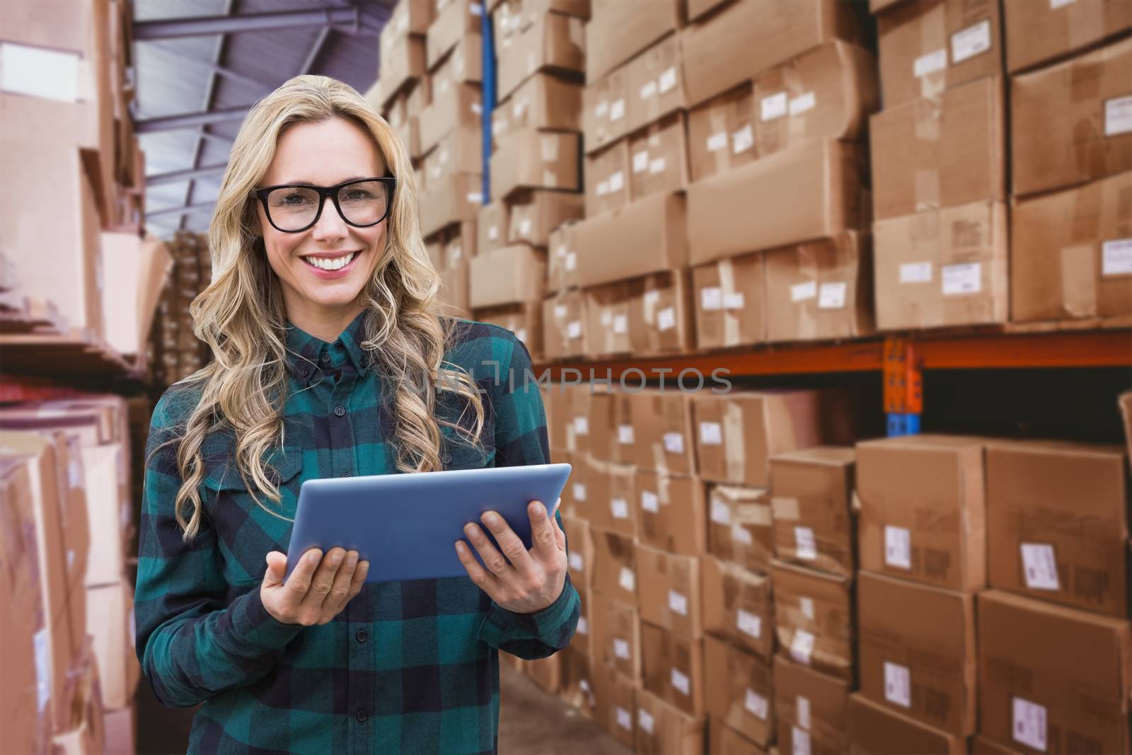 Pretty blonde with tablet against forklift in large warehouse