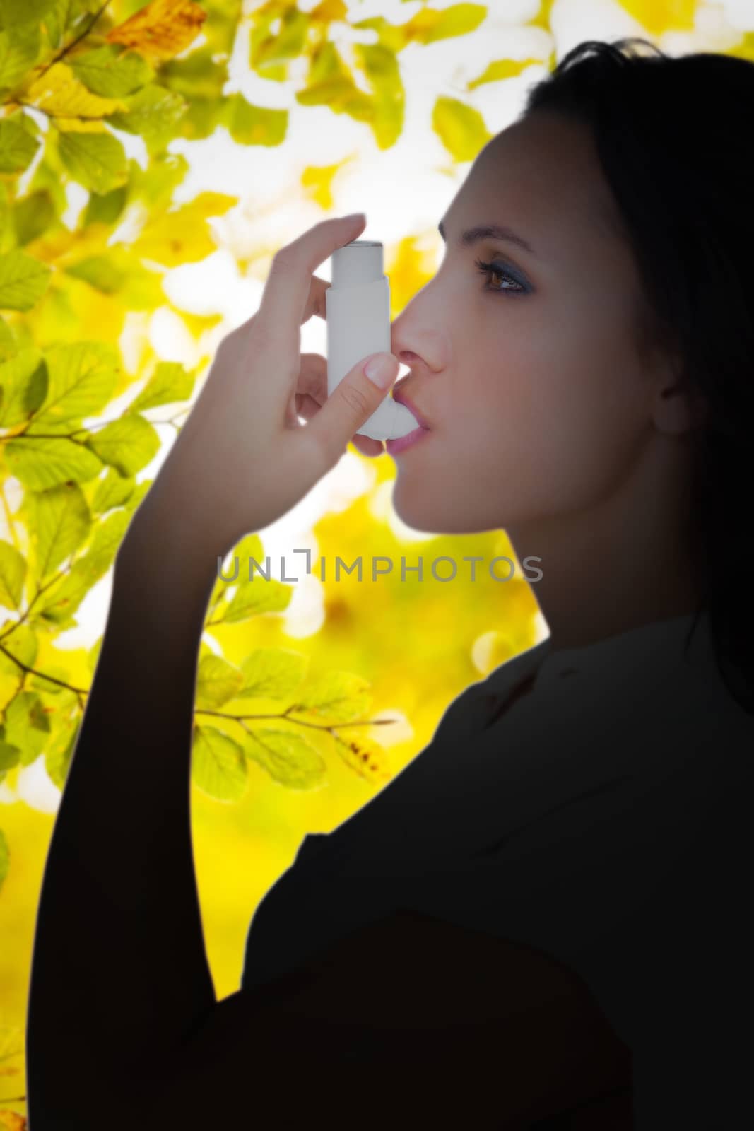 Asthmatic brunette using her inhaler  against detail shot of leaves