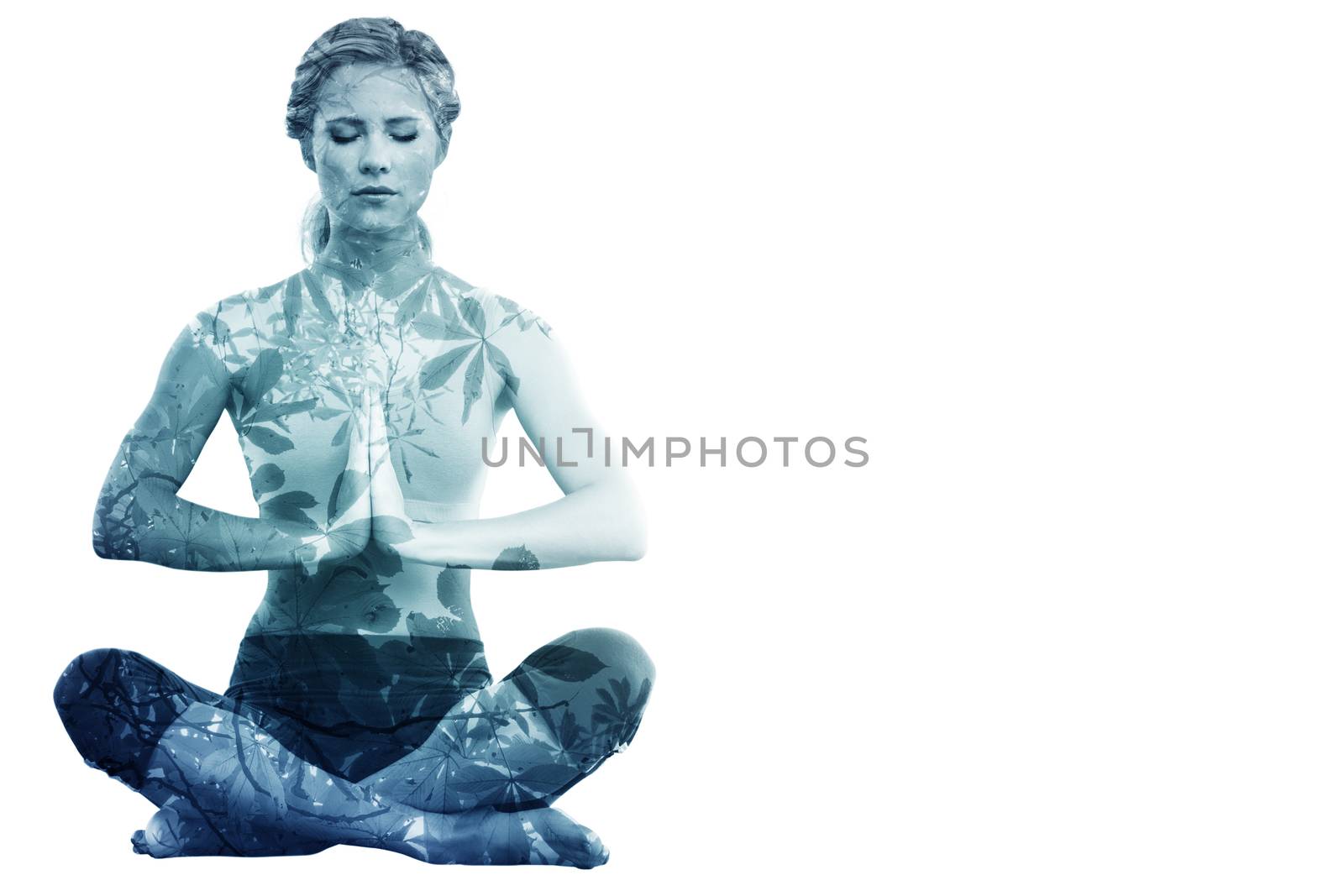 Calm blonde sitting in lotus pose with hands together against autumnal leaves against the clear sky