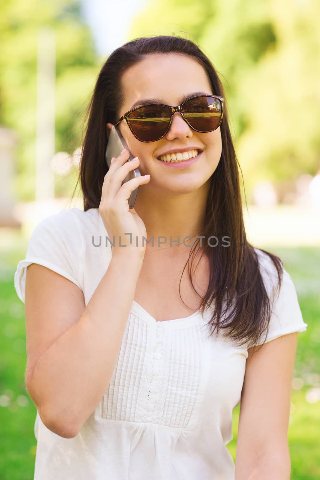 smiling young girl with smartphone outdoors by dolgachov