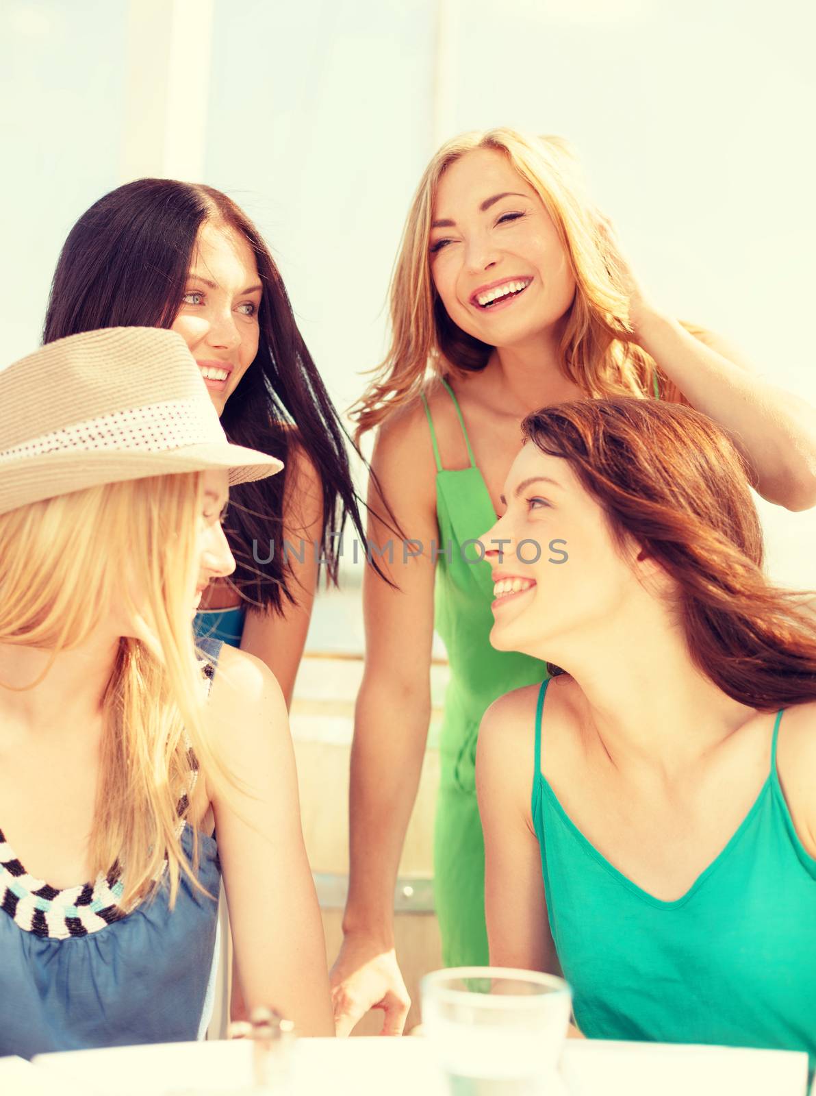 group of smiling girls in cafe on the beach by dolgachov