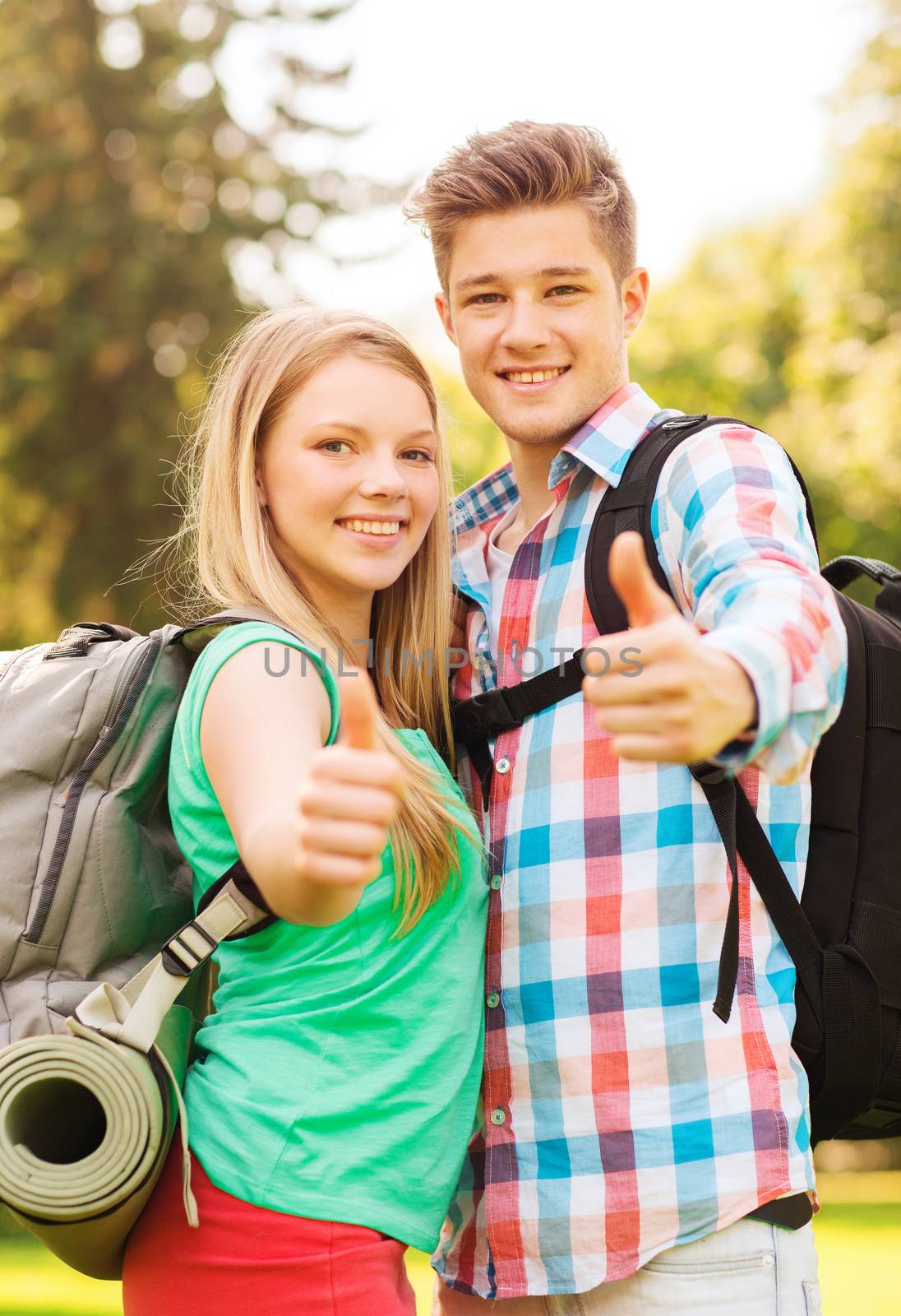 travel, vacation, tourism, gesture and friendship concept - smiling couple with backpacks showing thumbs up in nature