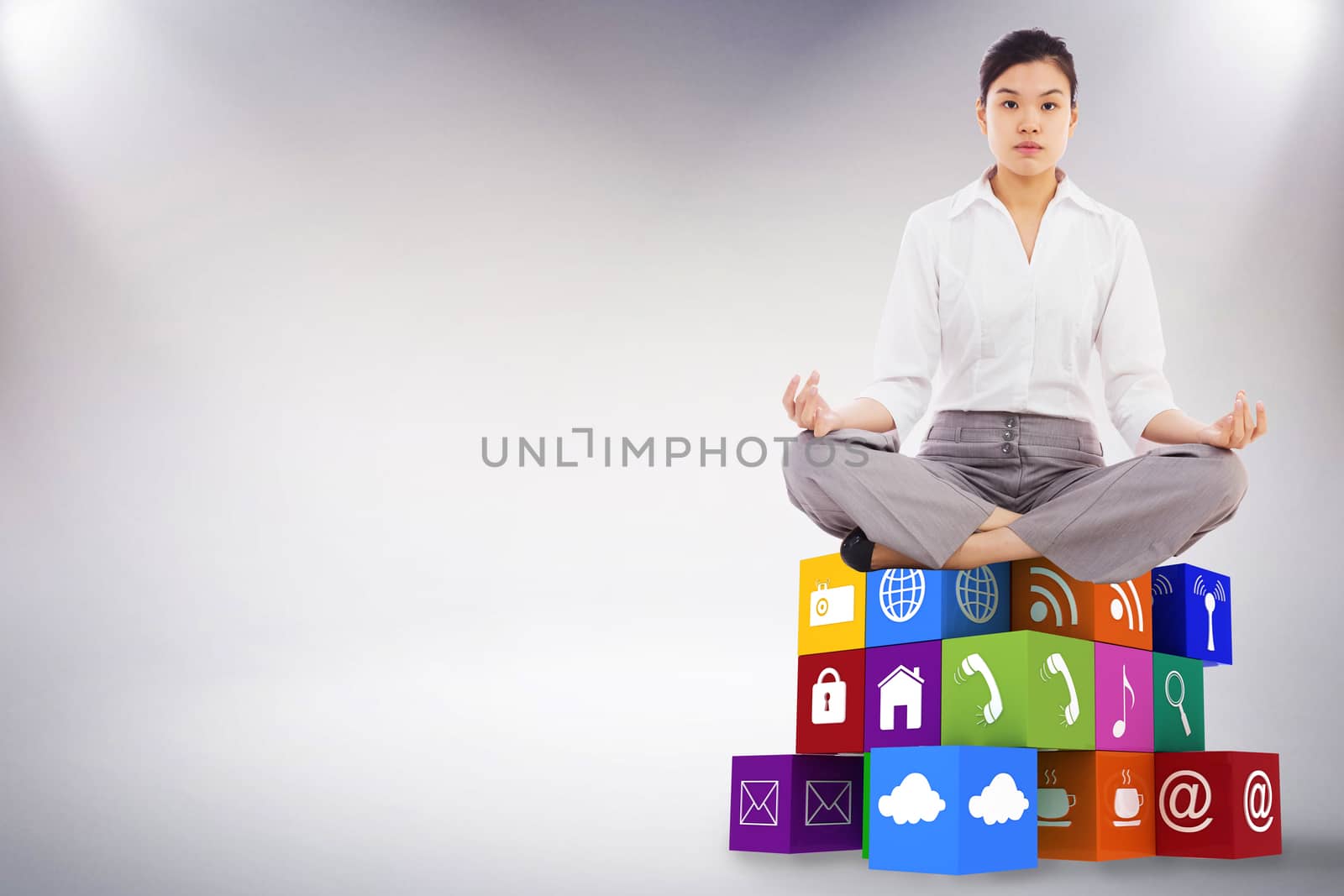 Businesswoman sitting in lotus pose against grey background