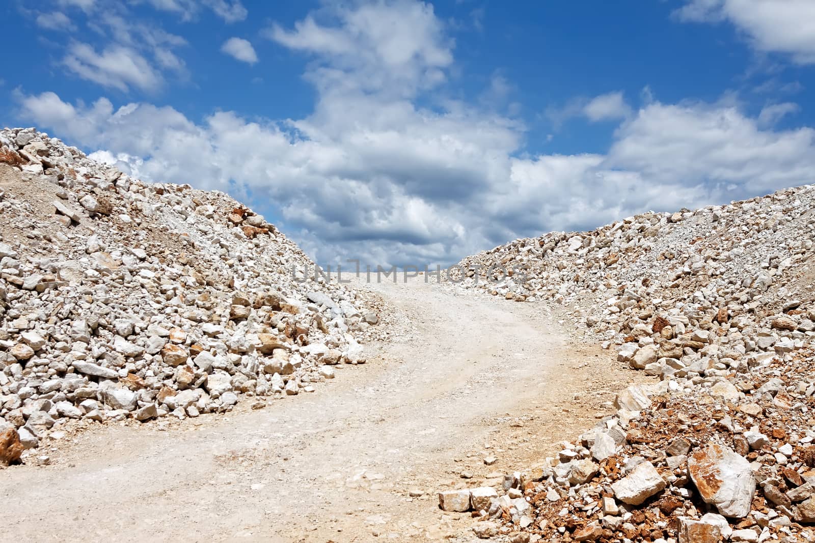 rocky road against blue sky with clouds