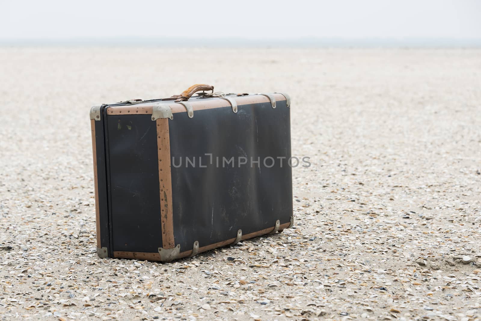 old vintage used leather suitcase for traveling on the sandy beach