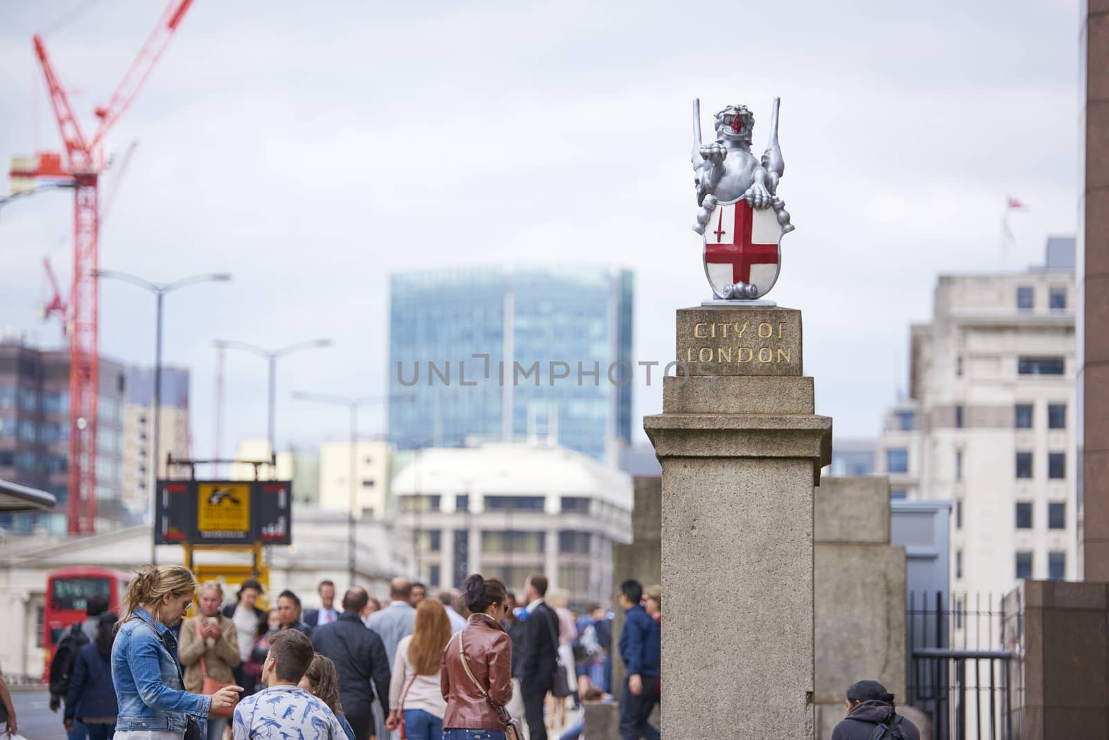 LONDON, UK - JUNE 23: Busy pavement on London Bridge, with City of London dragon in the foreground. June 23, 2015 in London.