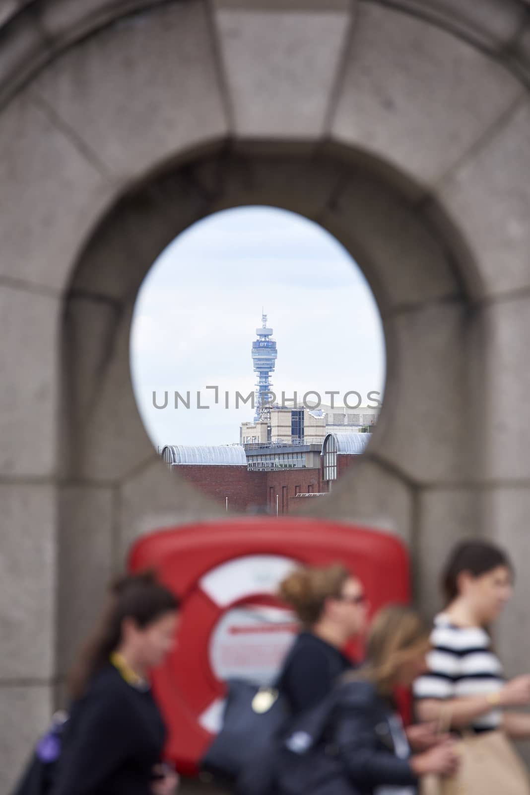 LONDON, UK - JUNE 23: The BT Tower framed in architectural detail, in the far background, with people passing by in the blurred foreground. June 23, 2015 in London.