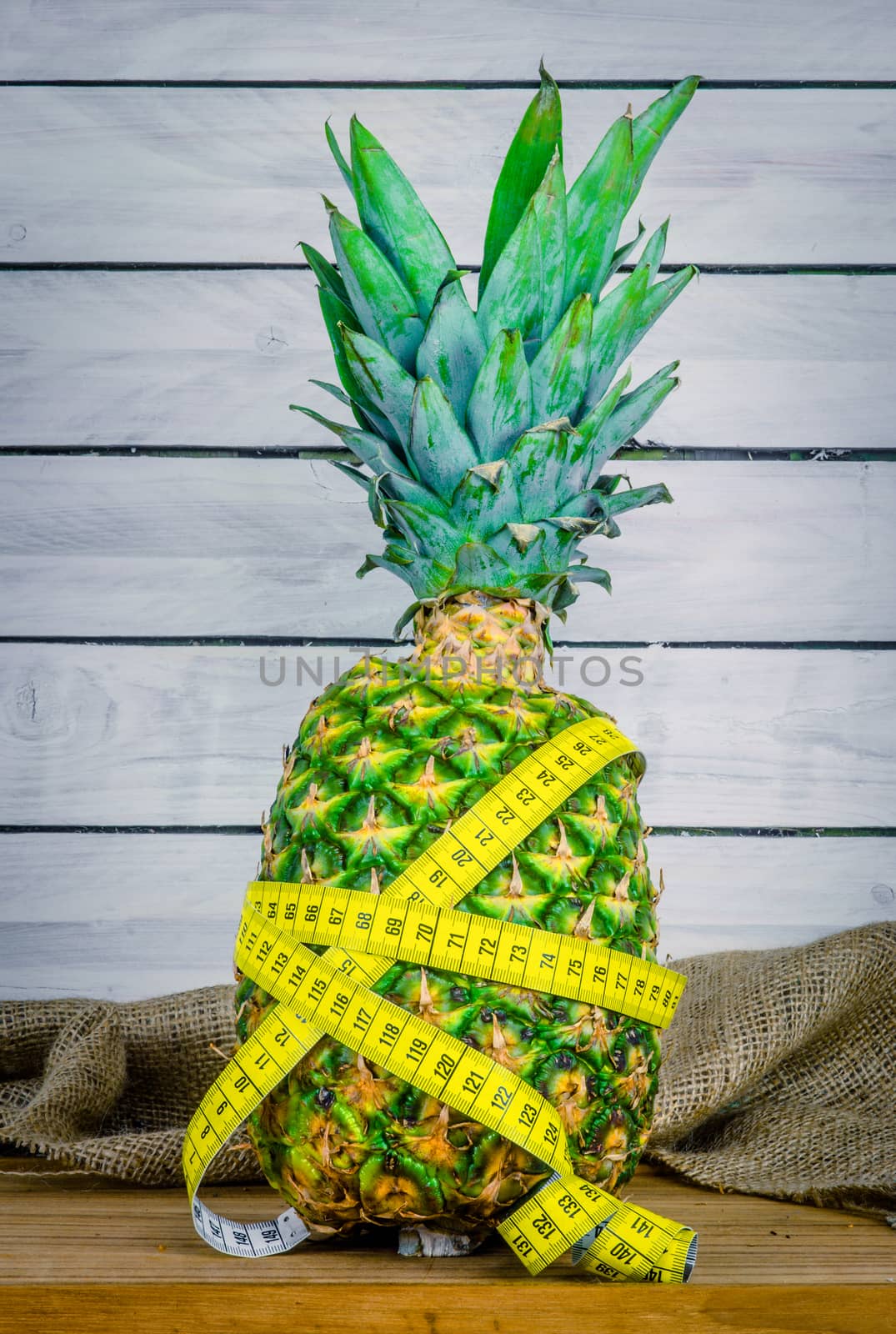 Pineapple with measure tape on a table by Sportactive
