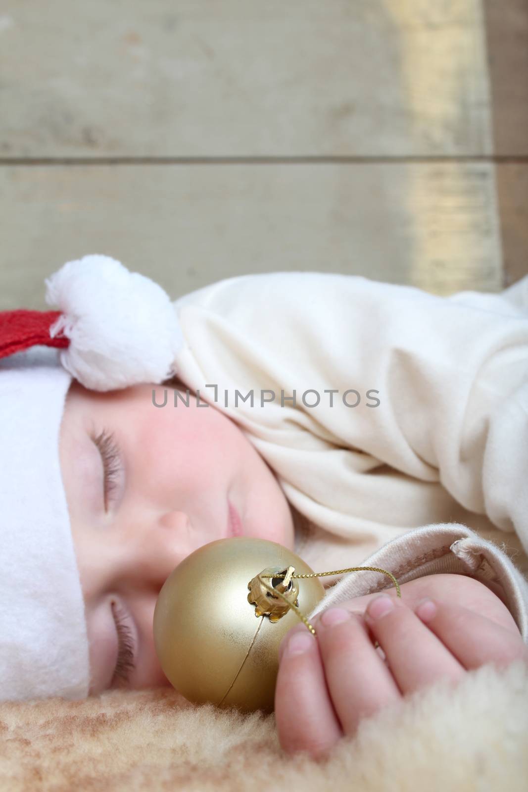 Sleeping christmas baby on a sheep skin rug wearing 