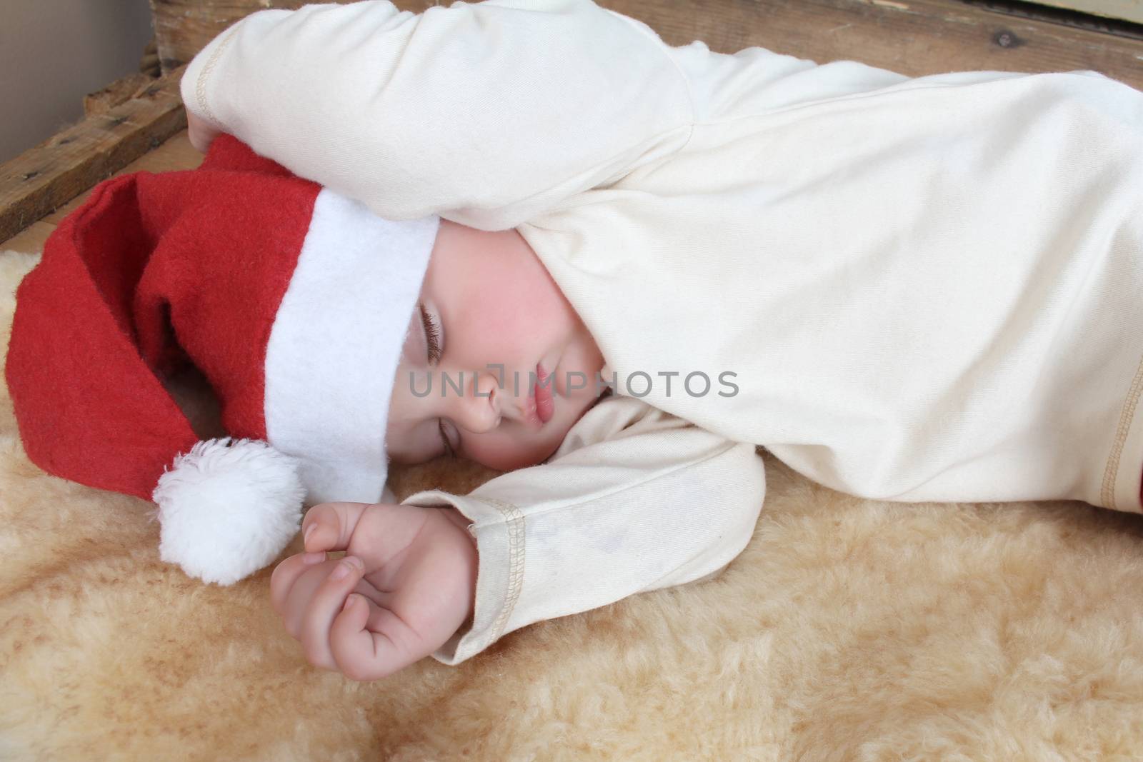 Sleeping christmas baby on a sheep skin rug wearing 