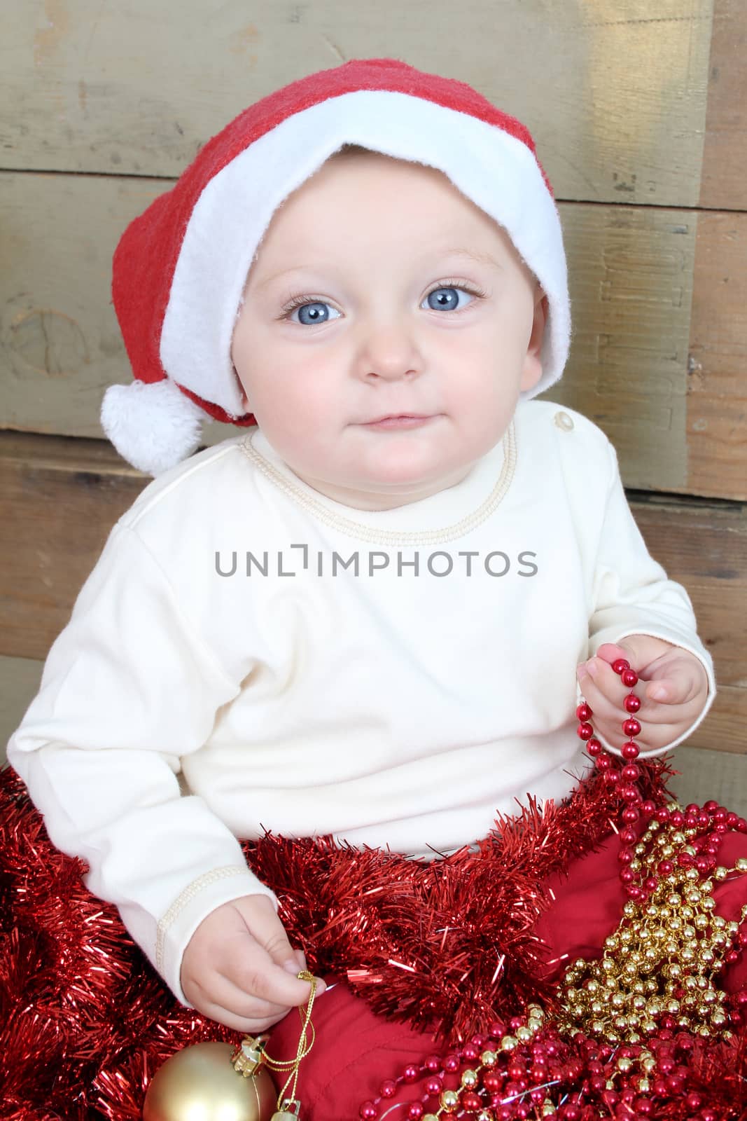 Baby boy wearing a christmas hat playing with decorations
