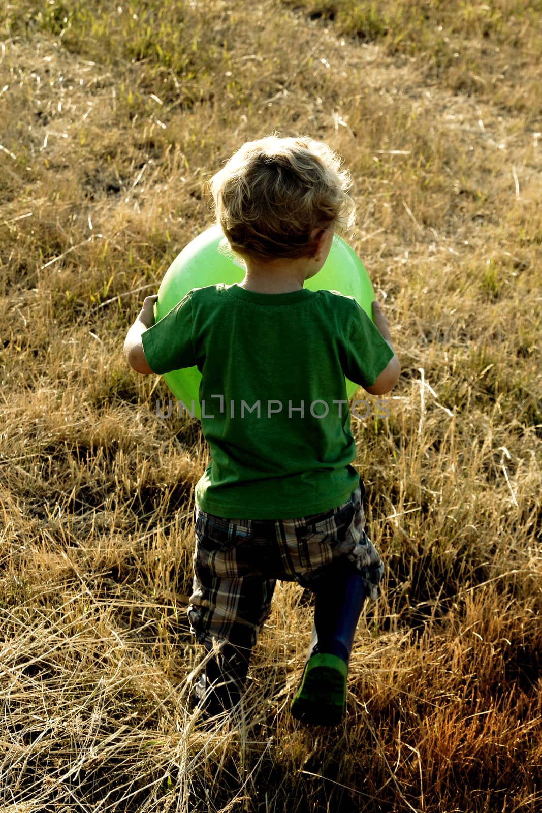 Blonde toddler boy playing outside in the field