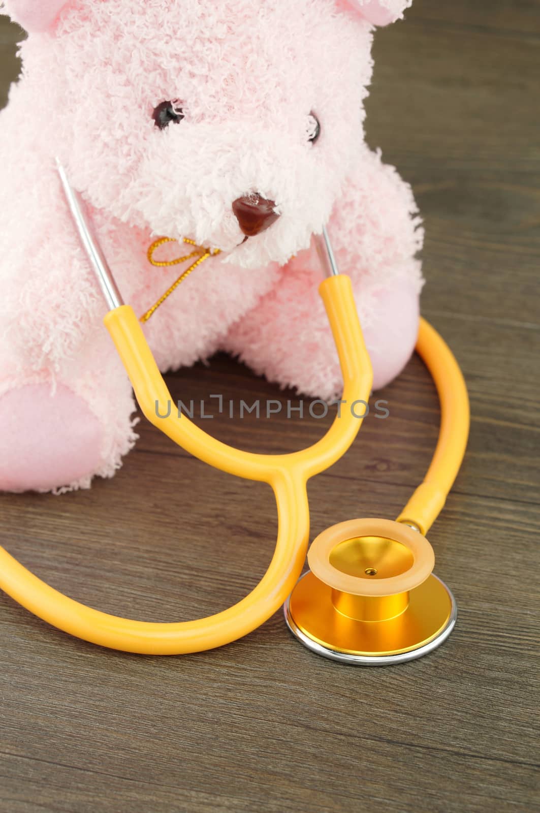 Pink doll holding gold color of stethoscope on its neck.                        