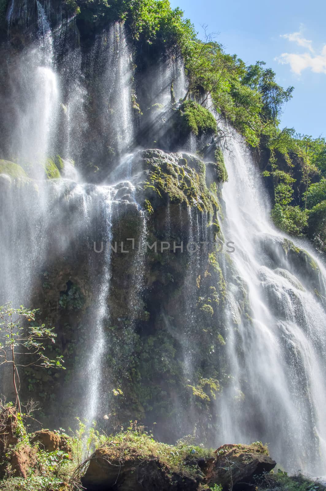 Bright sunlight shining on gorgeous tropical Cascada del Aguacero waterall in Chiapas, Mexico