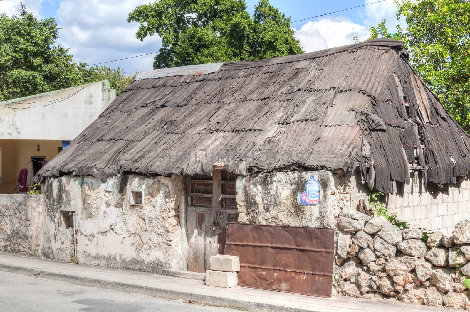 VALLADOLID, MEXICO - JANUARY 20, 2015: Obvious signs of wear are visible on this block and stucco home with rusty worn corrugated metal roof in Valladolid, Yucatan