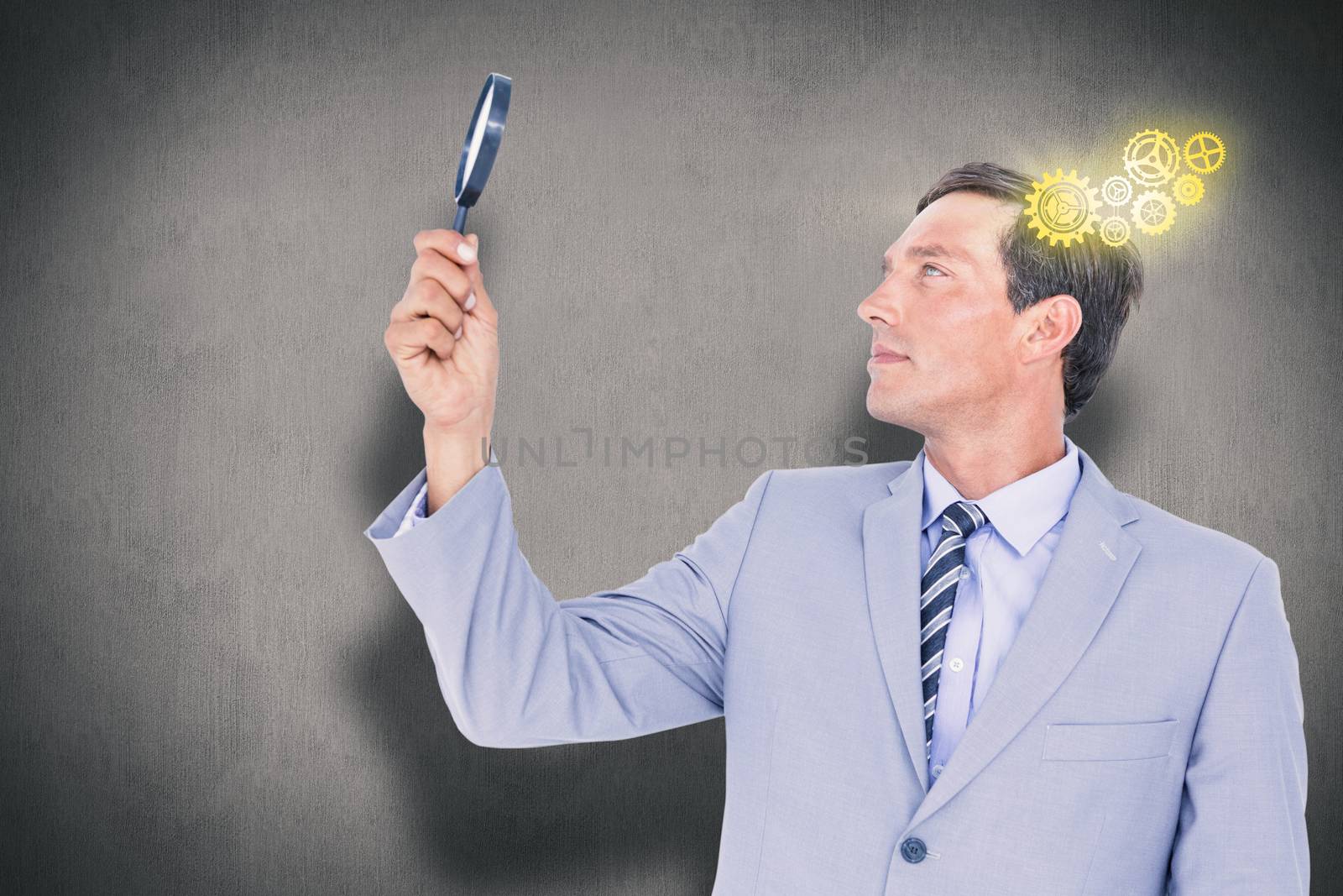 concentrated businessman using magnifying glass against white and grey background