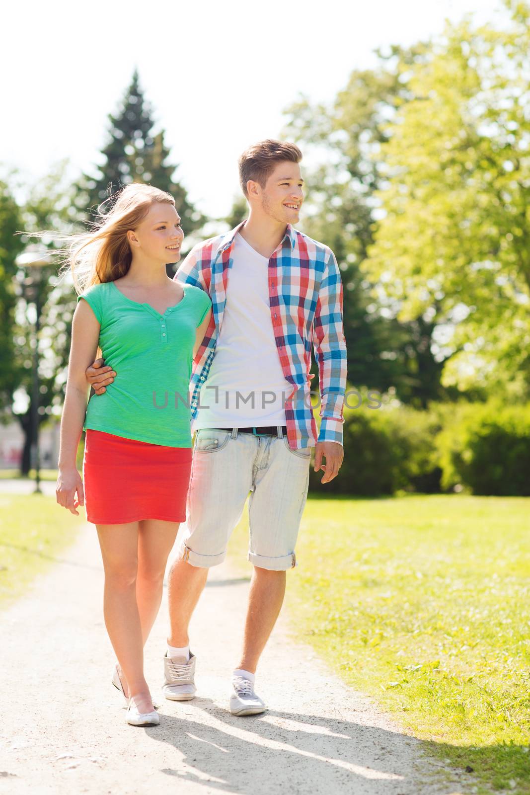 holidays, vacation, love and friendship concept - smiling couple walking in park