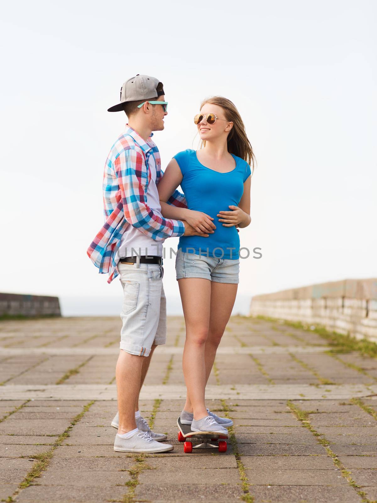 smiling couple with skateboard outdoors by dolgachov