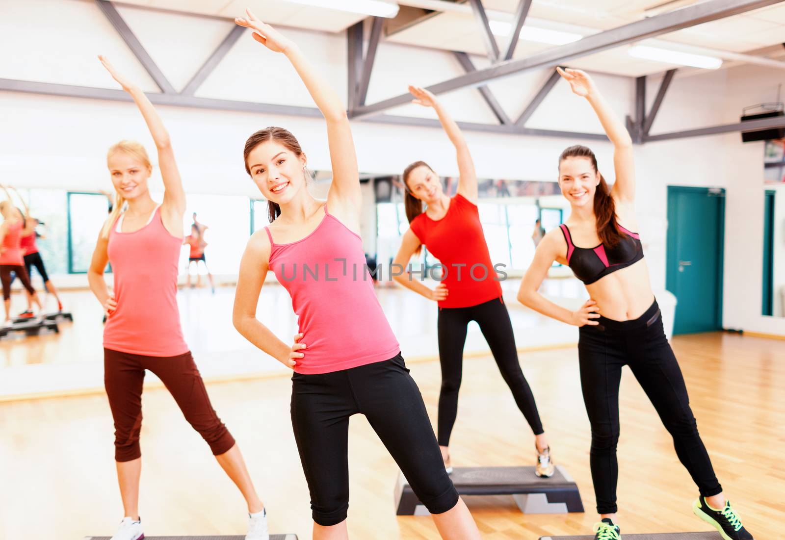 group of smiling female stretching in gym by dolgachov