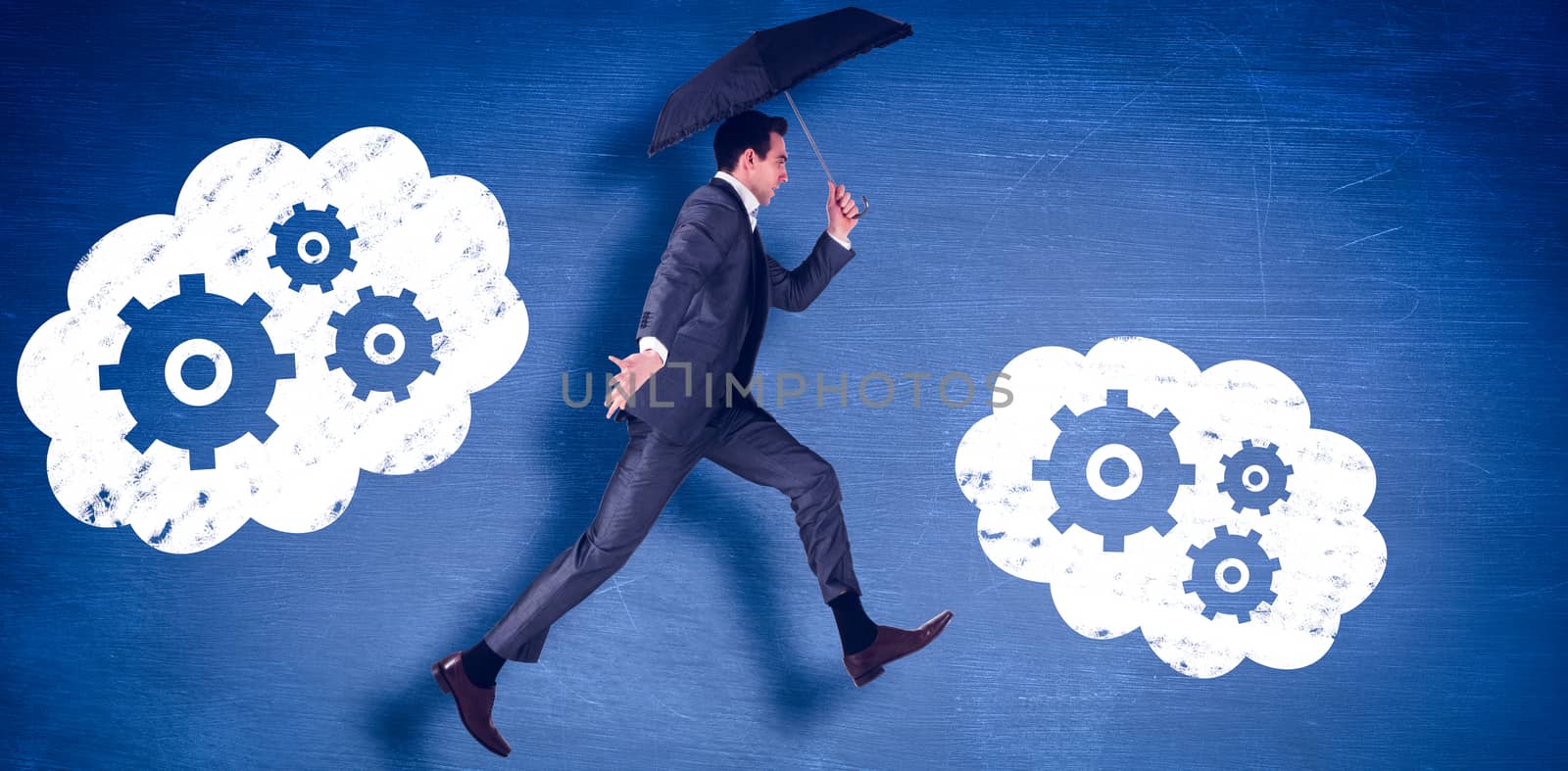 Businessman jumping holding an umbrella against blue chalkboard